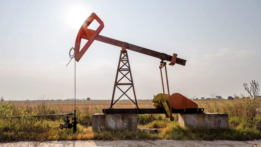 Side view of red oil pump during the day in a Texas field